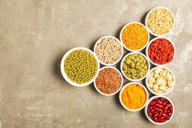 Photo of Different superfoods in bowls on grey table, flat lay. Space for text