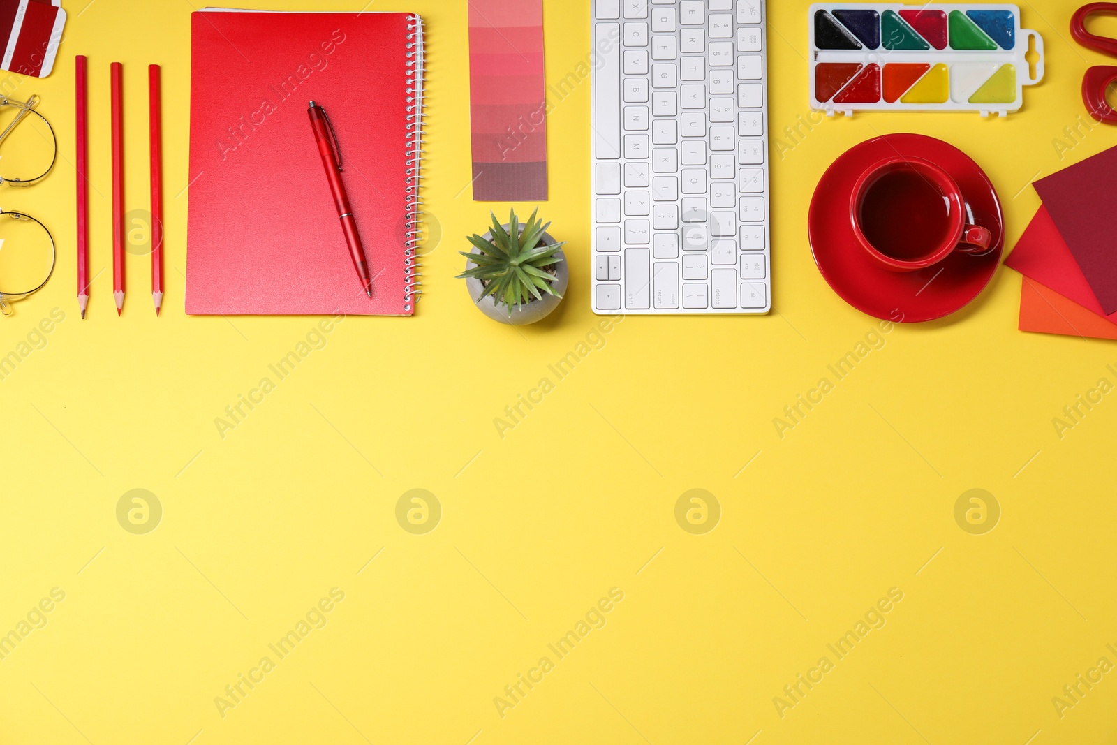 Photo of Designer's workplace. Flat lay composition with stationery, keyboard and cup of coffee on yellow background, space for text