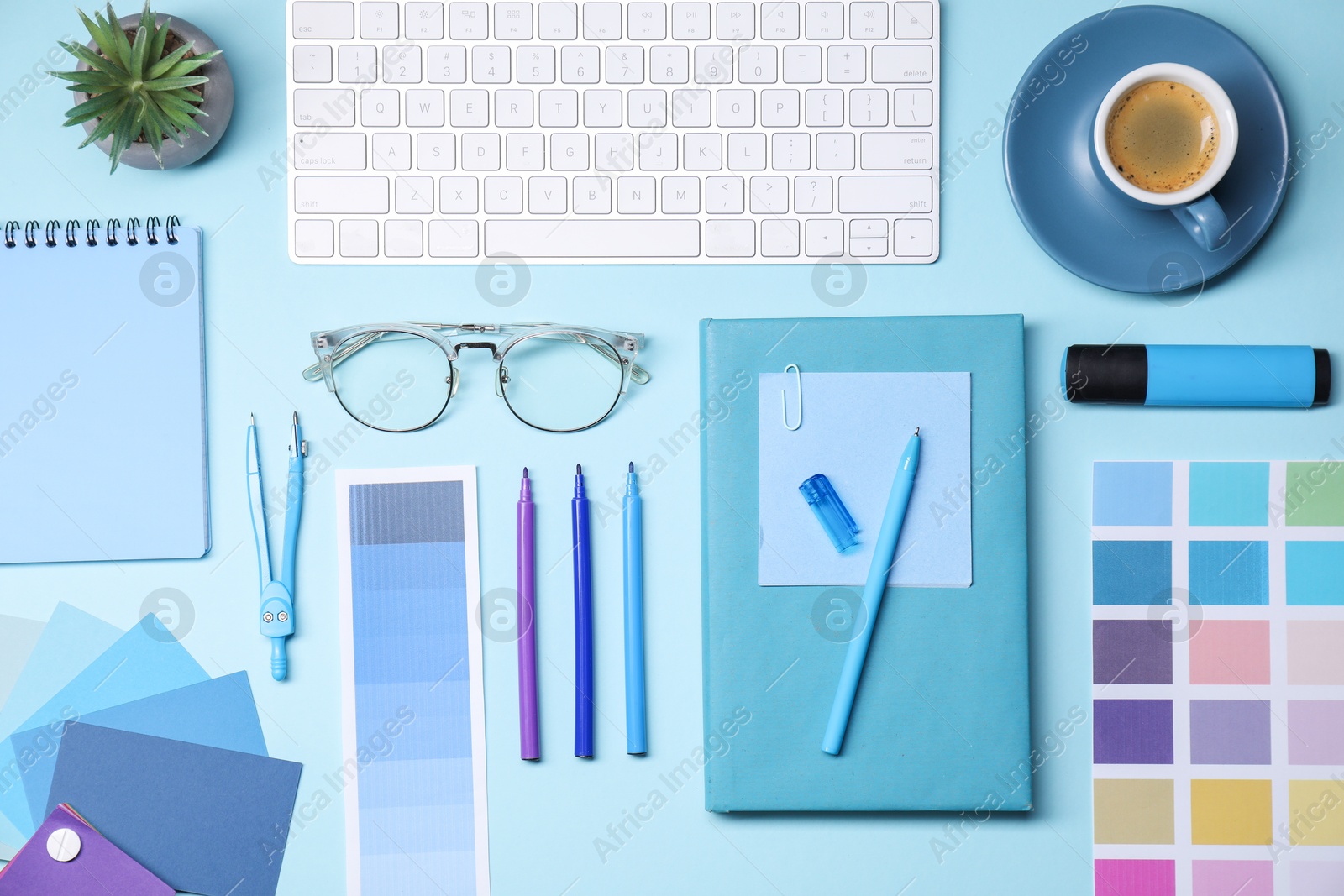 Photo of Designer's workplace. Flat lay composition with stationery and keyboard on light blue background