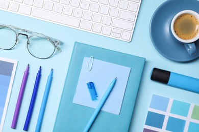 Photo of Designer's workplace. Flat lay composition with stationery and keyboard on light blue background