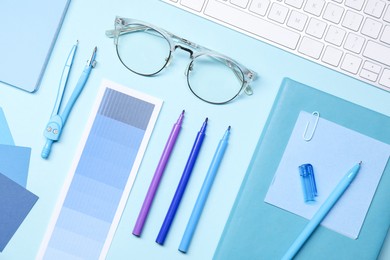 Photo of Designer's workplace. Flat lay composition with stationery and keyboard on light blue background