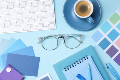 Photo of Designer's workplace. Flat lay composition with stationery and keyboard on light blue background