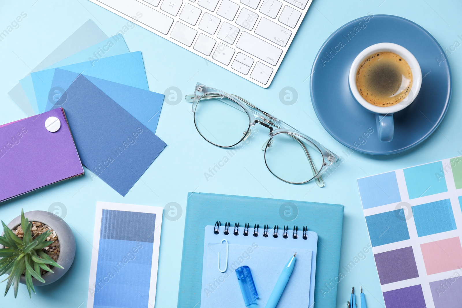 Photo of Designer's workplace. Flat lay composition with stationery and keyboard on light blue background