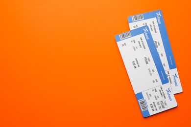 Photo of Travel agency. Flight tickets on orange background, top view. Space for text