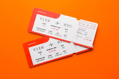 Photo of Travel agency. Flight tickets on orange background, top view