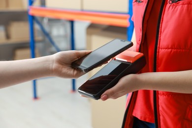 Photo of Woman paying for service with credit card via terminal indoors, closeup