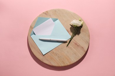 Photo of Paper envelope with letter, flower and pen on pink background, flat lay. Mockup for design