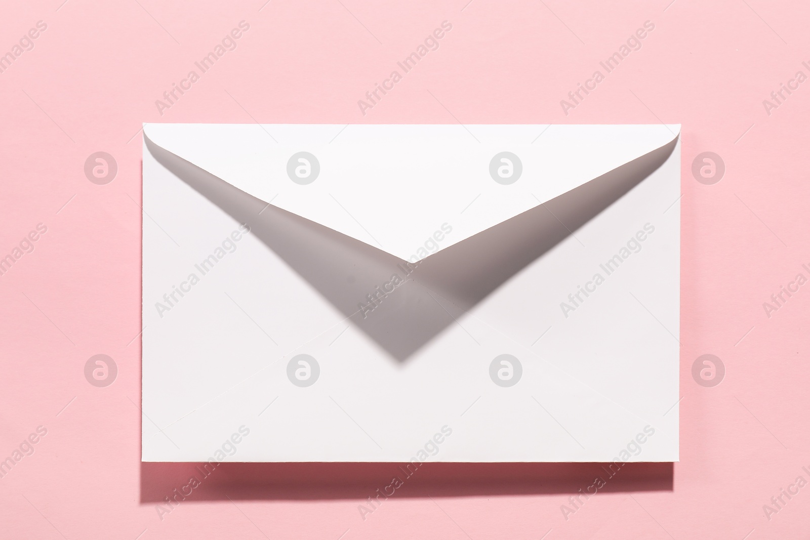 Photo of Paper envelope on pink background, top view. Mockup for design