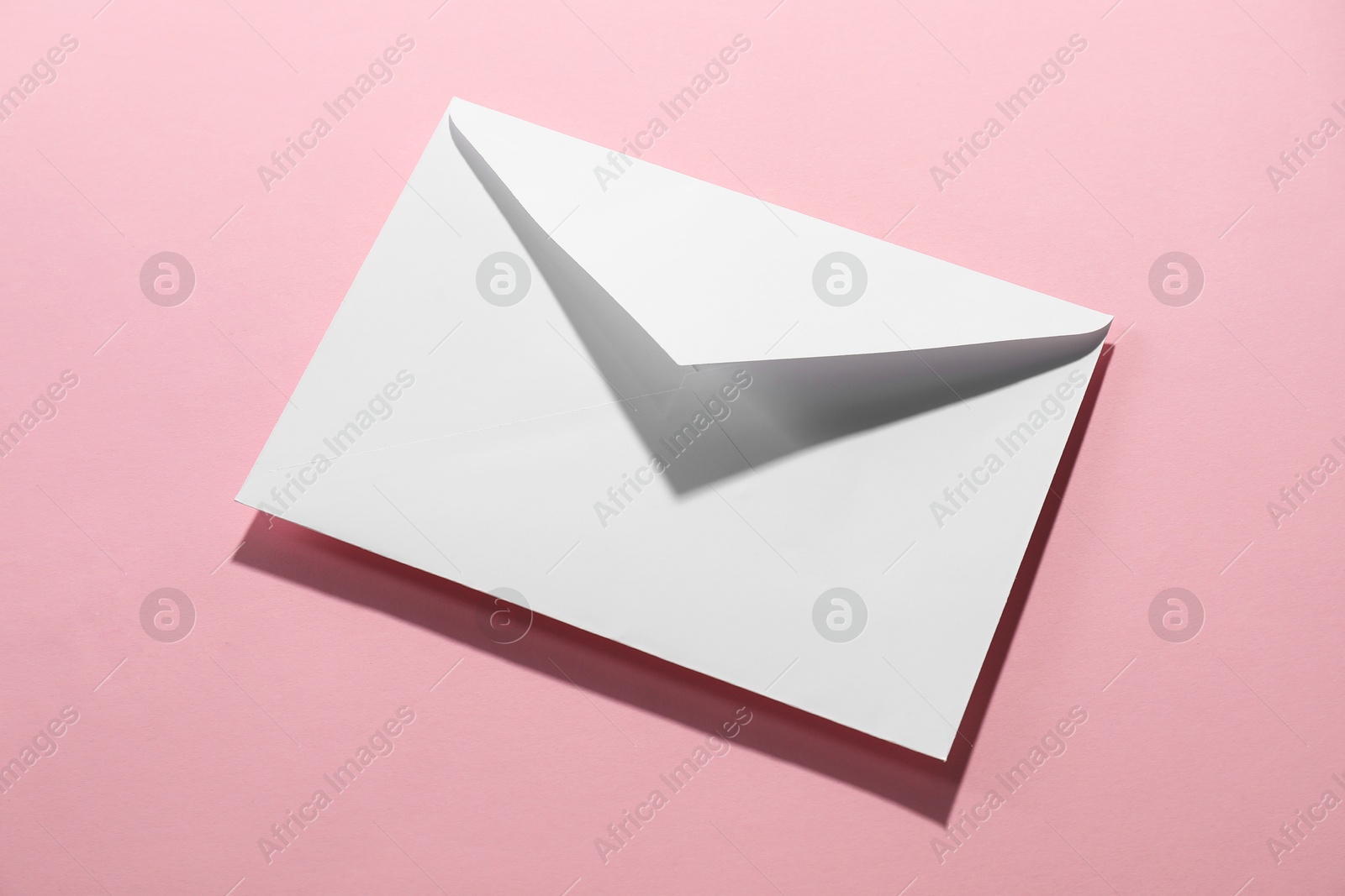 Photo of Paper envelope on pink background, above view. Mockup for design