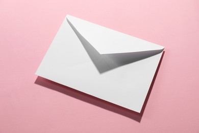 Paper envelope on pink background, above view. Mockup for design