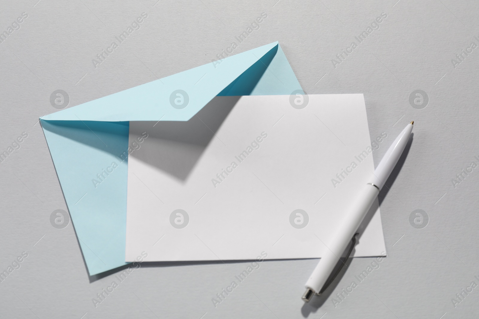 Photo of Paper envelope with letter and pen on grey background, top view. Mockup for design