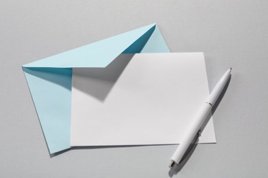 Paper envelope with letter and pen on grey background, top view. Mockup for design