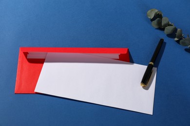 Paper envelopes, fountain pen and eucalyptus branch on blue background, above view. Mockup for design