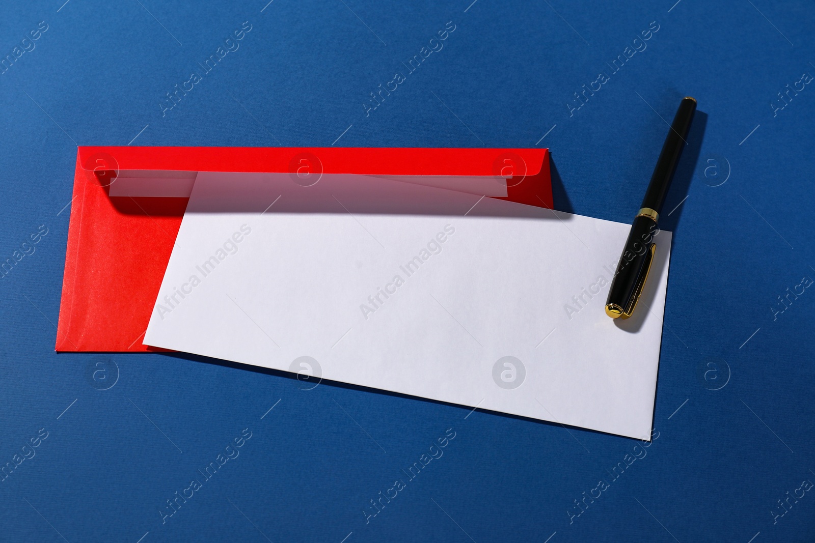 Photo of Paper envelopes and fountain pen on blue background, above view. Mockup for design