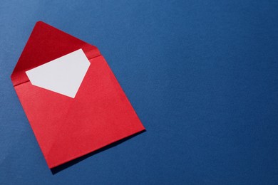 Photo of Paper envelope with letter on blue background, above view. Mockup for design