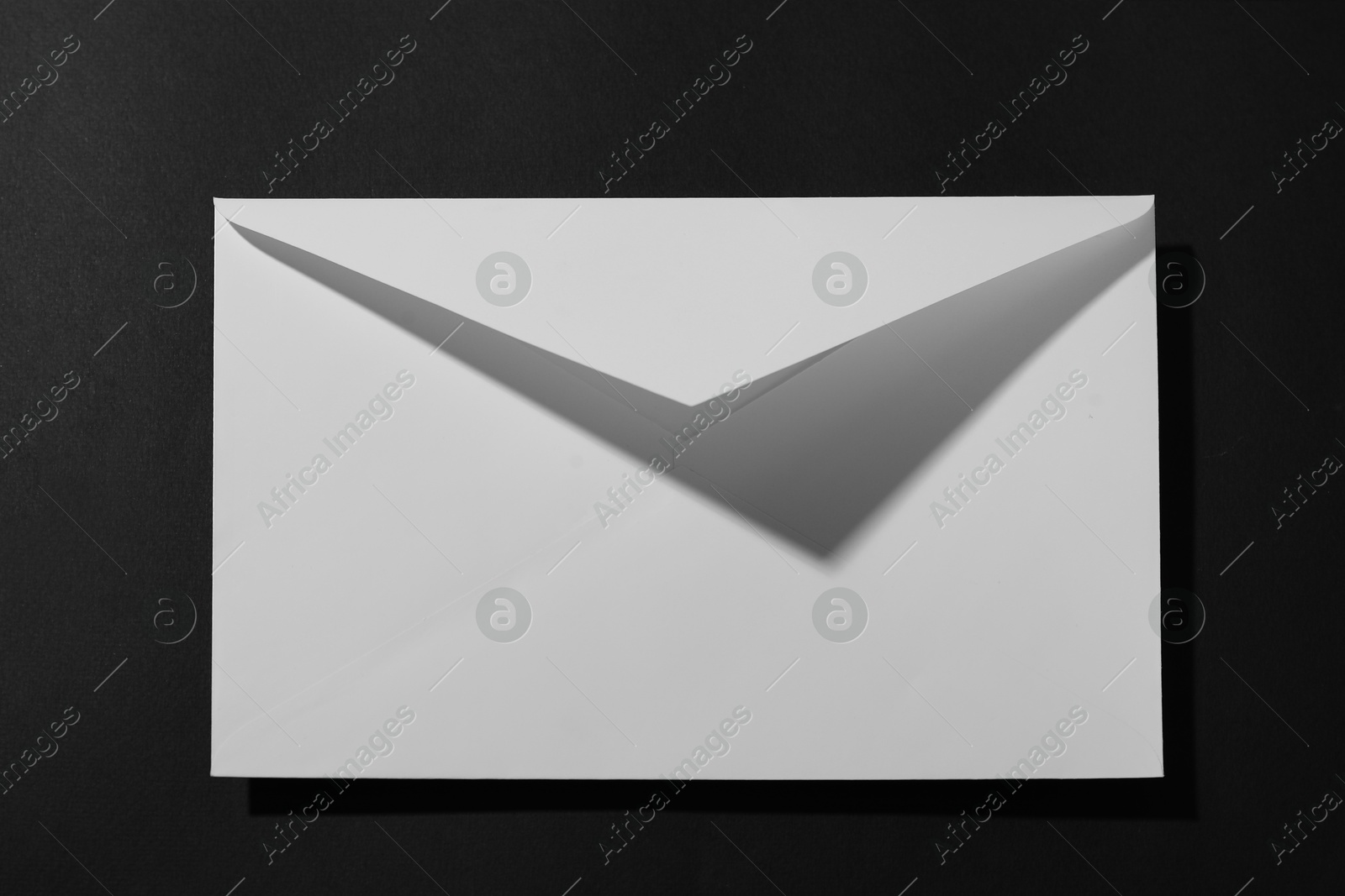 Photo of Paper envelope on black background, above view. Mockup for design