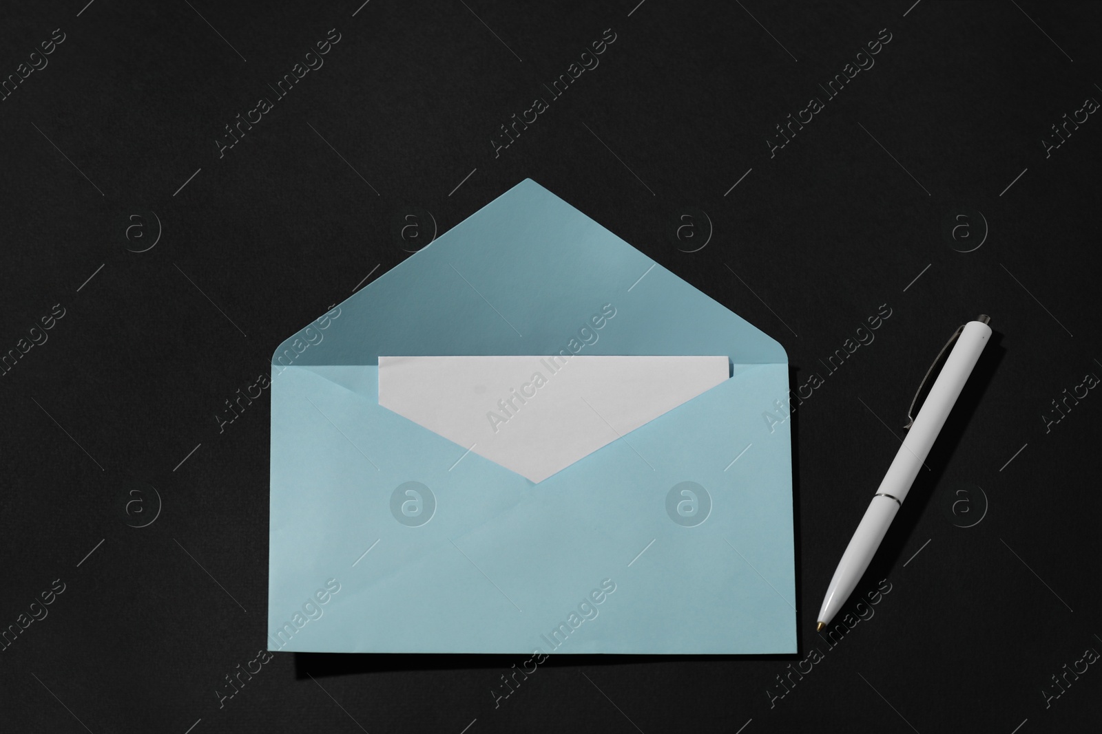 Photo of Paper envelope with letter and pen on black background, above view. Mockup for design