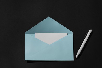 Photo of Paper envelope with letter and pen on black background, above view. Mockup for design