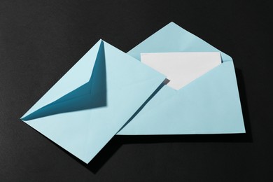 Photo of Paper envelopes with letter on black background, above view. Mockup for design