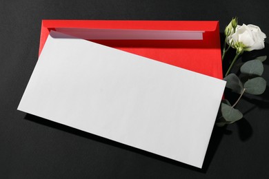 Photo of Paper envelopes, flower and eucalyptus branch on black background, above view. Mockup for design