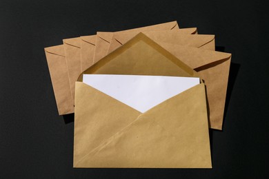 Kraft paper envelopes with letter on black background, above view. Mockup for design