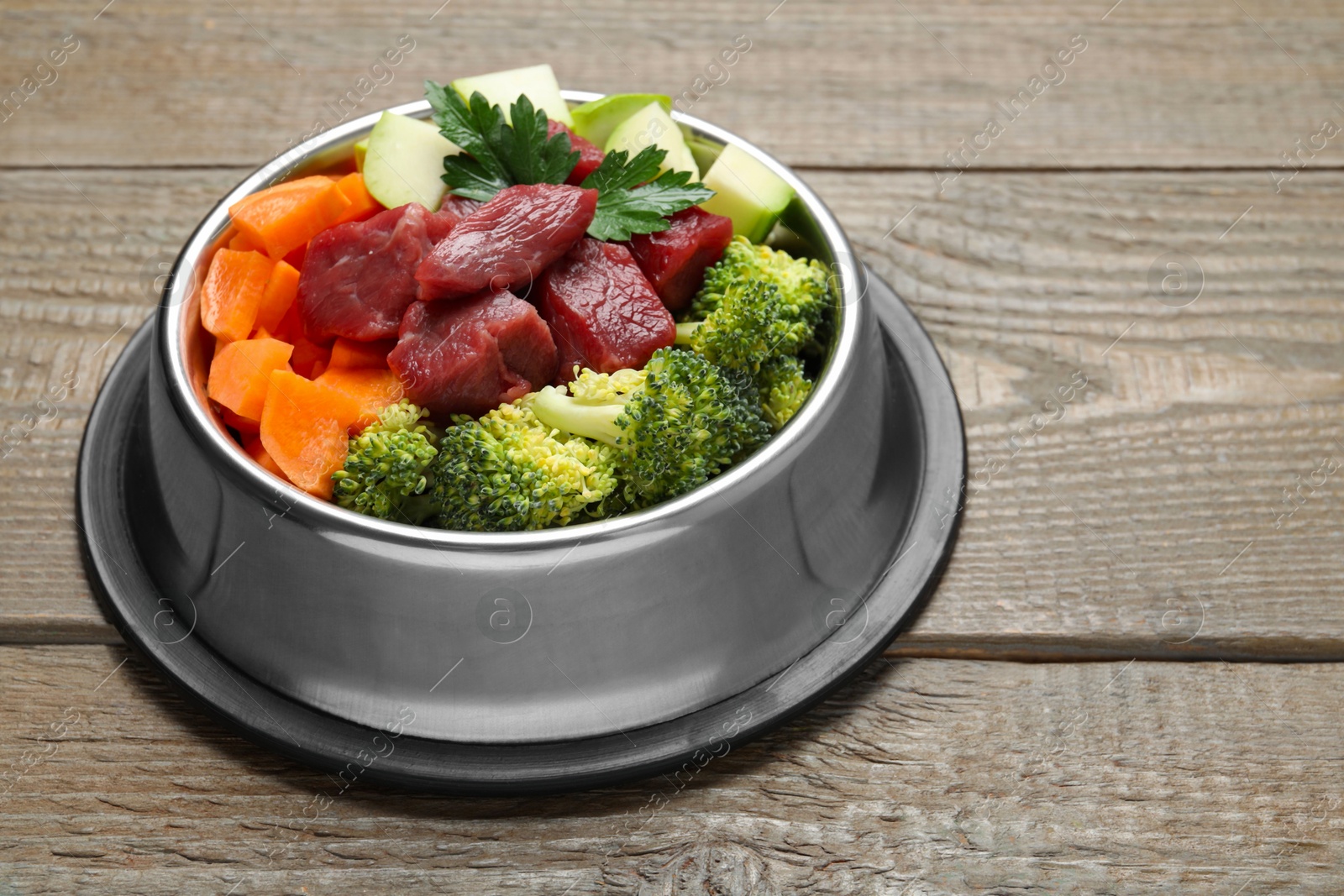 Photo of Fresh natural pet food in feeding bowl on wooden table, closeup