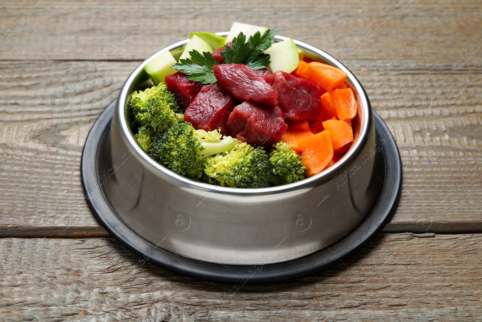 Photo of Fresh natural pet food in feeding bowl on wooden table, closeup