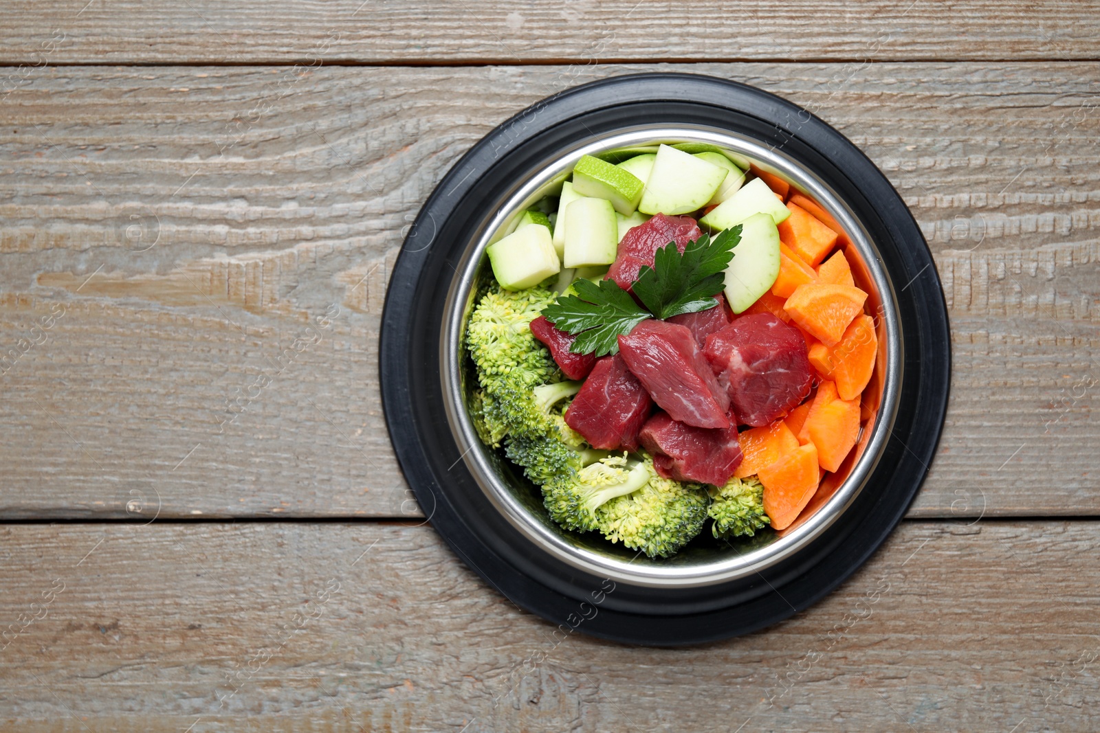 Photo of Fresh natural pet food in feeding bowl on wooden table, top view. Space for text