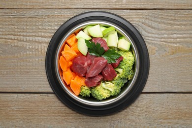 Photo of Fresh natural pet food in feeding bowl on wooden table, top view