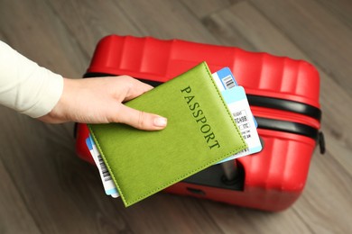 Photo of Woman with passport, tickets and suitcase indoors, closeup