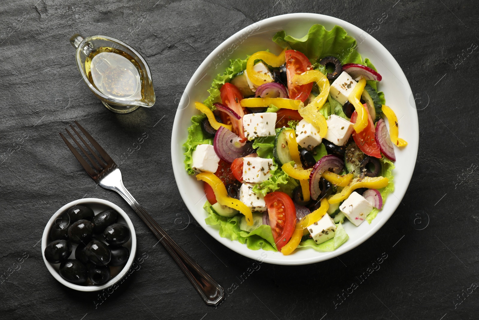 Photo of Delicious fresh Greek salad served on black table, flat lay