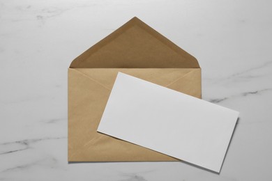 Kraft paper envelope with letter on white marble background, top view. Mockup for design