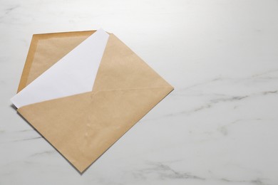 Kraft paper envelope with letter on white marble background, top view. Mockup for design