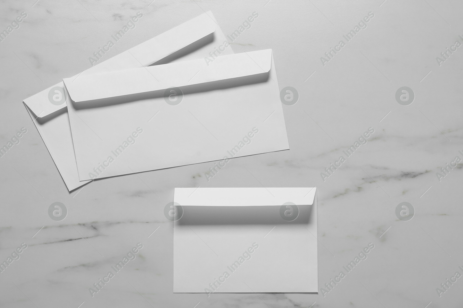 Photo of Paper envelopes on white marble background, flat lay. Mockup for design