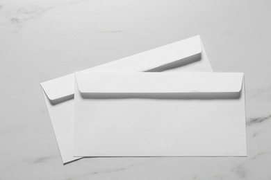 Paper envelopes on white marble background, top view. Mockup for design