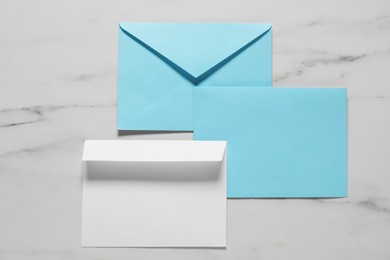 Photo of Paper envelopes on white marble background, flat lay. Mockup for design