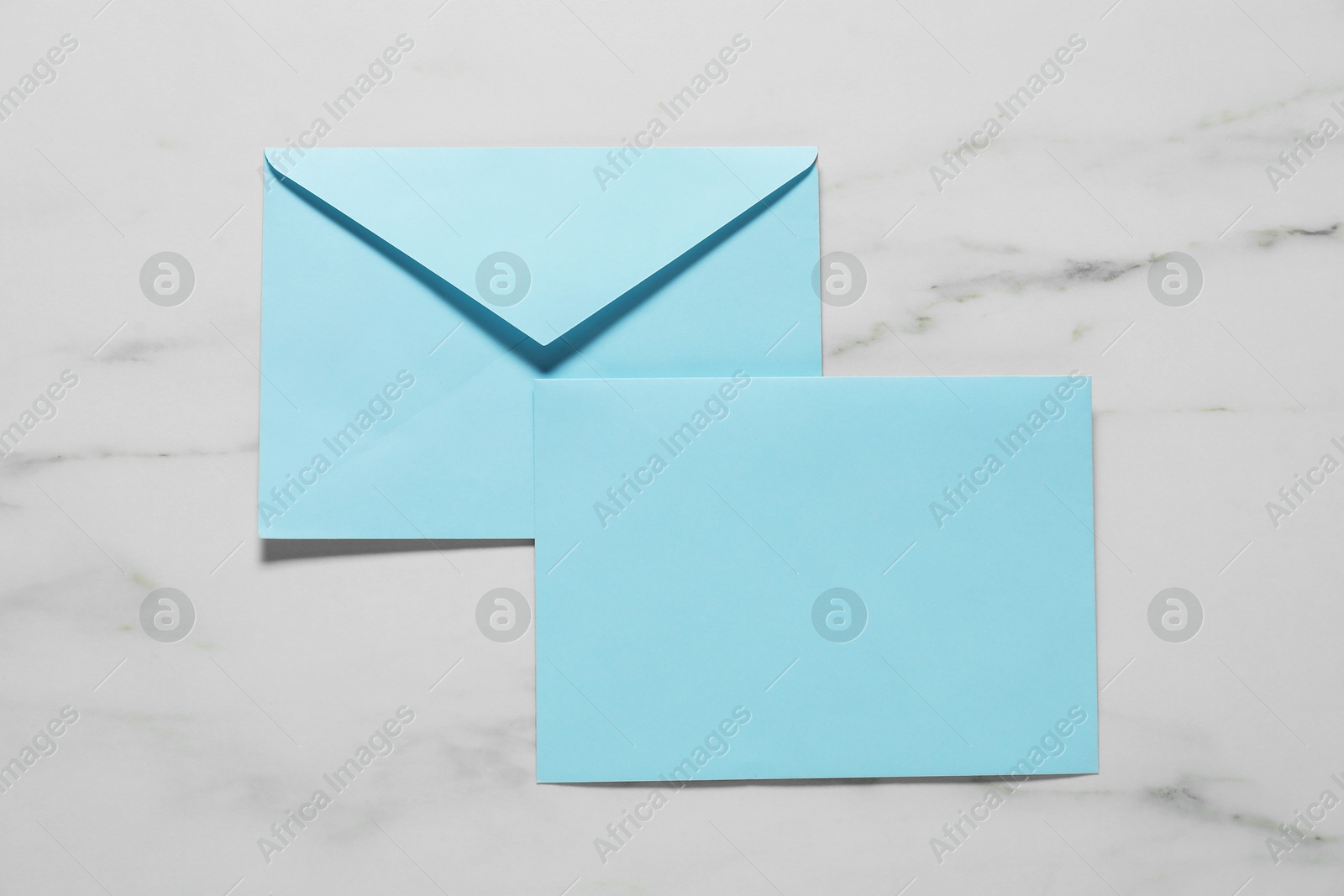 Photo of Paper envelopes on white marble background, top view. Mockup for design