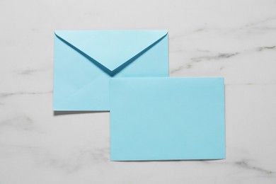 Paper envelopes on white marble background, top view. Mockup for design