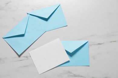 Photo of Paper envelopes with letter on white marble background, flat lay. Mockup for design