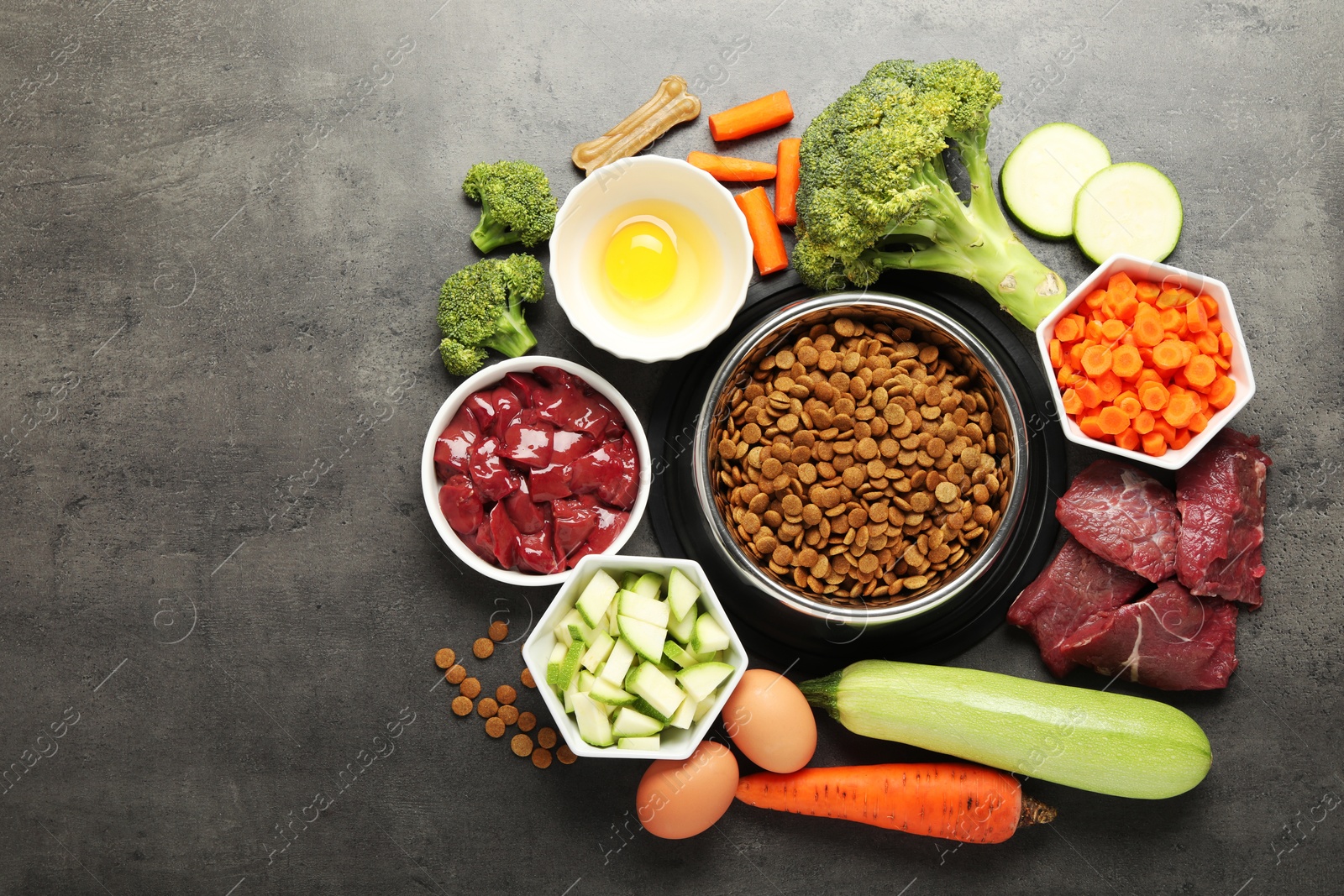 Photo of Dry pet food and natural products on grey table, top view