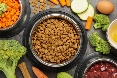 Photo of Dry pet food and natural products on grey table, top view