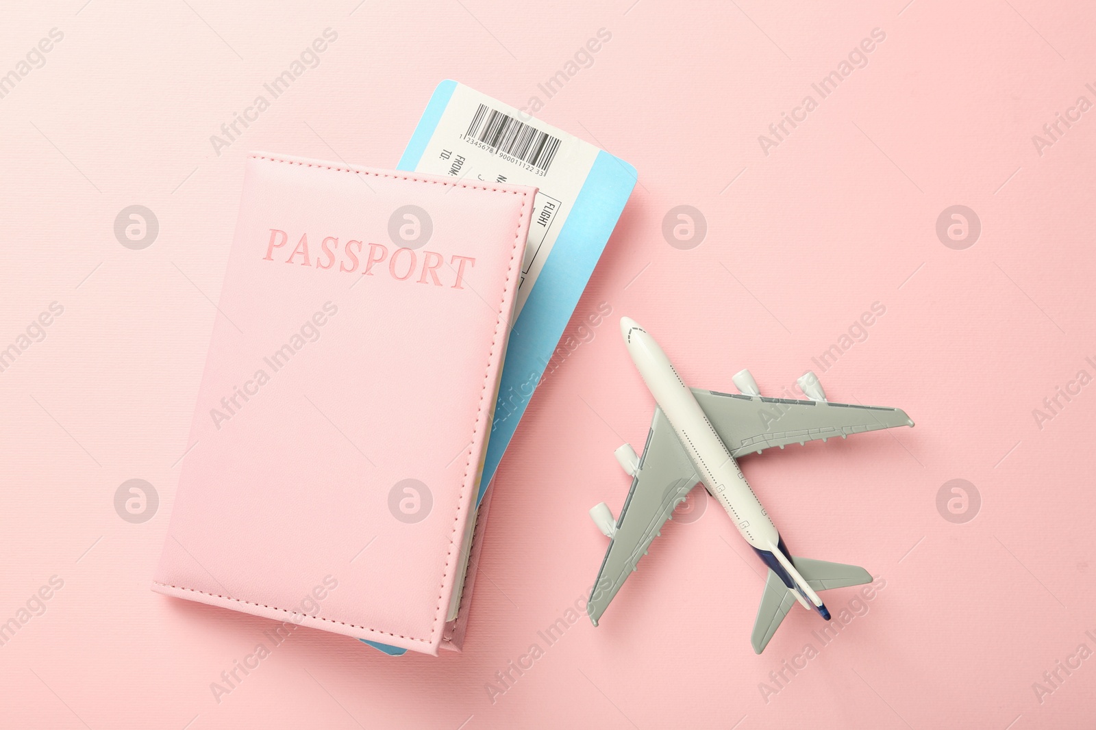 Photo of Passport with ticket and plane model on pink background, flat lay