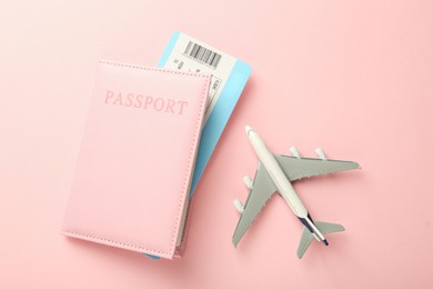 Photo of Passport with ticket and plane model on pink background, flat lay