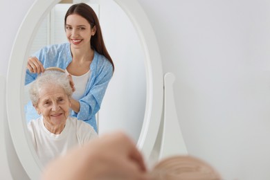 Photo of Woman brushing senior lady with brush indoors