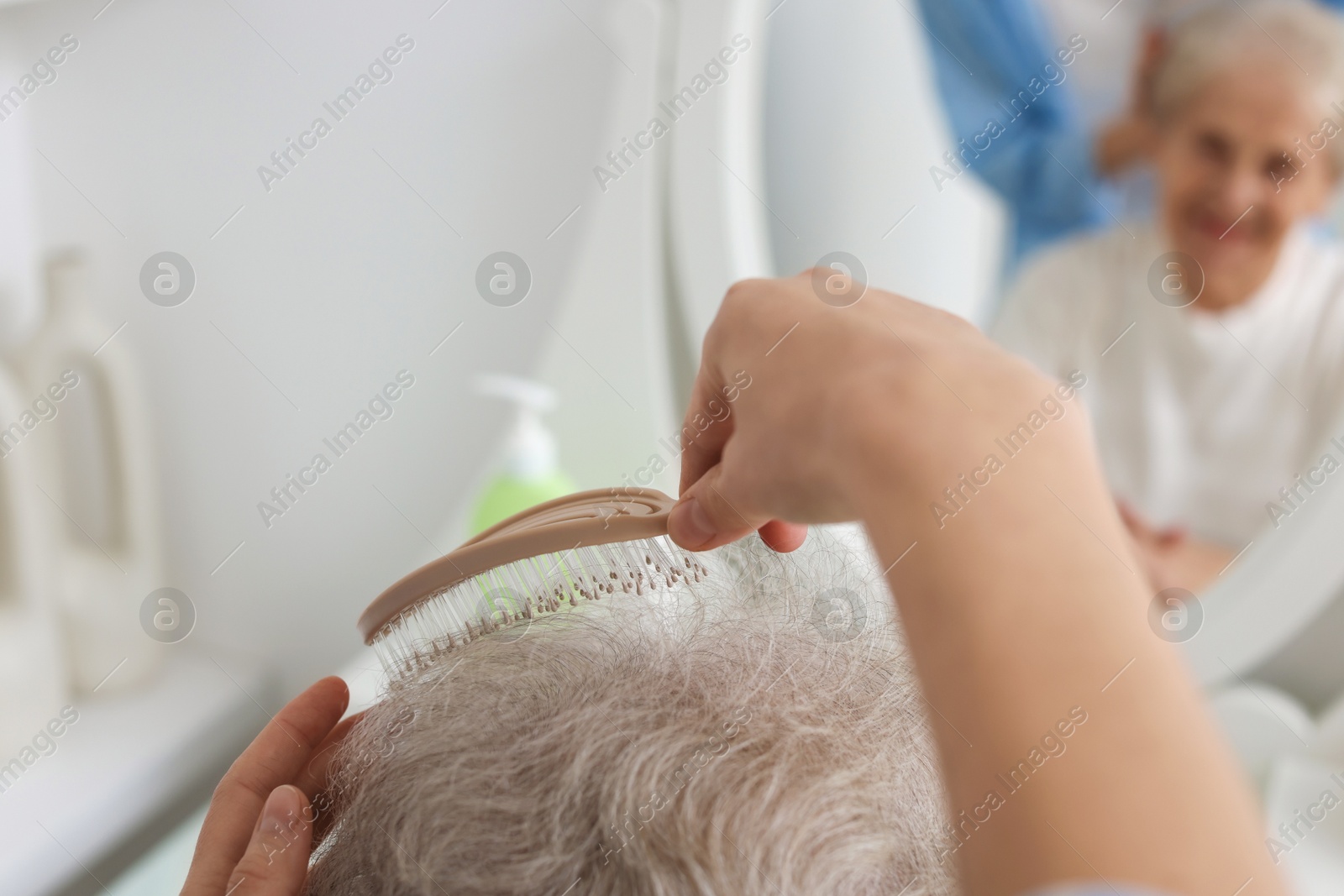 Photo of Woman brushing senior lady with brush indoors, closeup