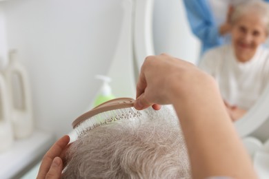 Photo of Woman brushing senior lady with brush indoors, closeup