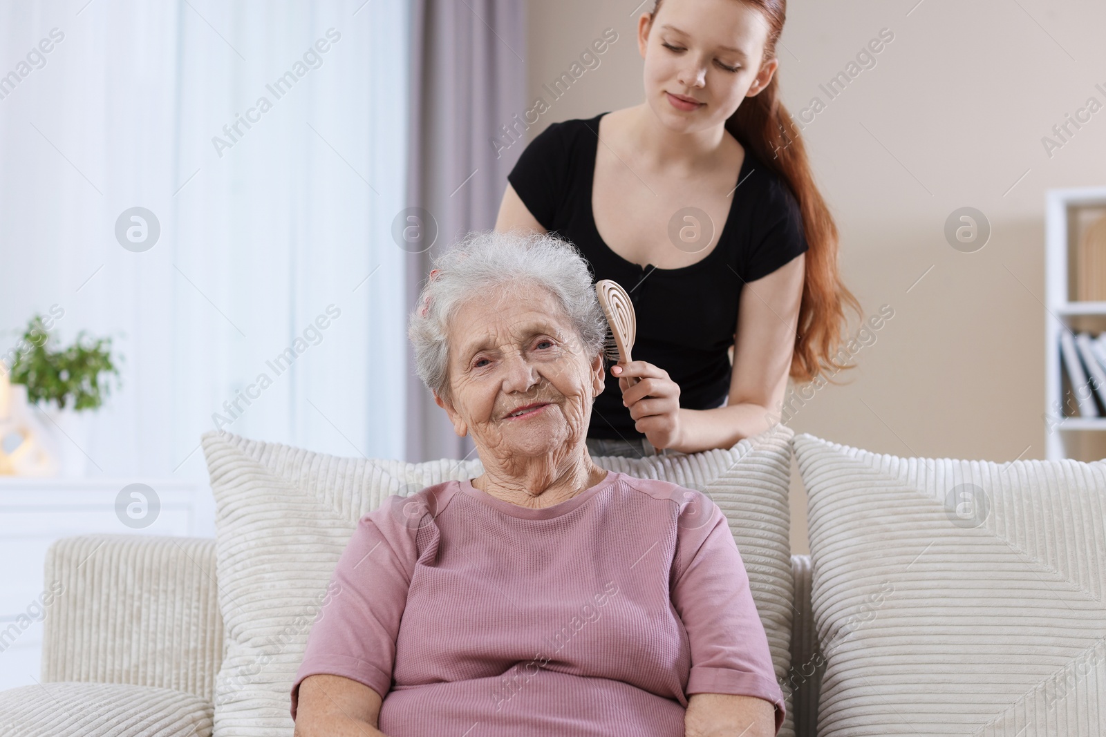 Photo of Granddaughter brushing her grandmother with brush at home