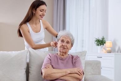 Photo of Woman brushing senior lady with comb indoors