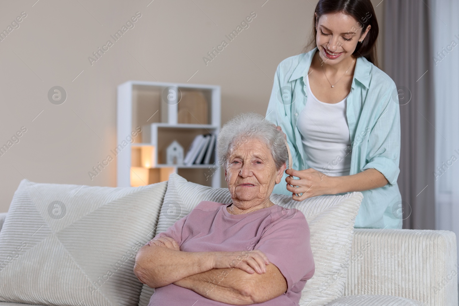 Photo of Woman brushing senior lady with brush indoors