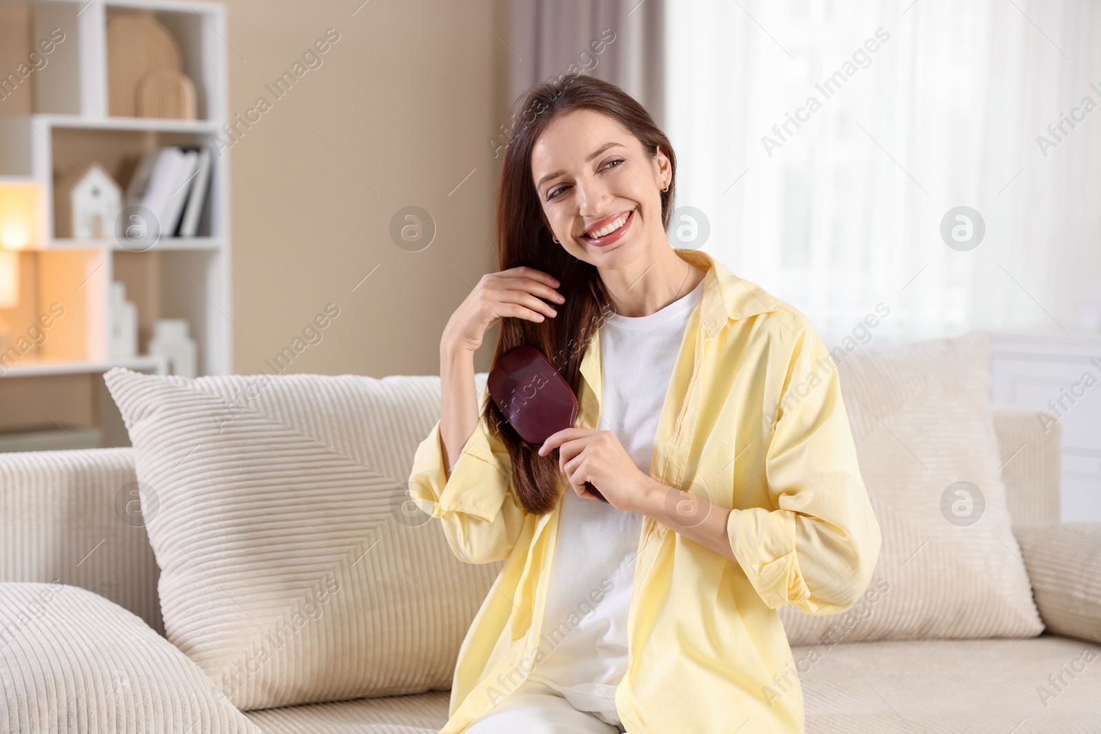 Photo of Smiling woman brushing her hair at home